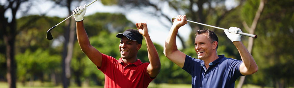 Two happy golfers on the golf course, smiling and laughing with their clubs over their heads